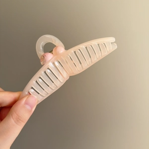 Elegant peach translucent wheat ear hair claw clip shown in hand for size and texture