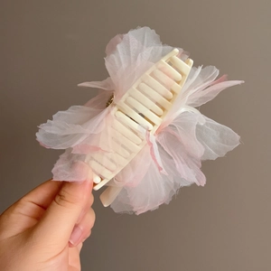 Dettaglio di un grande fermaglio a forma di fiore in rete rosa con petali leggeri