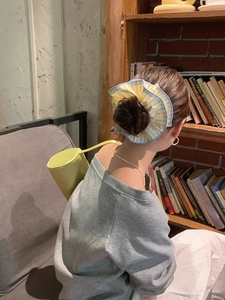 Detail showing the large yellow striped scrunchie with blue edging on a messy bun