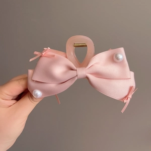 Dettaglio della molletta per capelli con fiocco di raso rosa e perle bianche eleganti