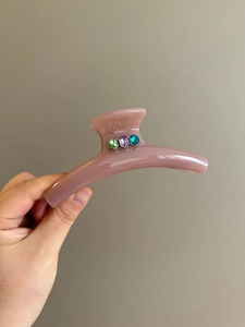 Detail of a dusty pink hair claw clip featuring three colorful oval sparkling rhinestones