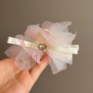 Dettaglio di una grande pinza per capelli con petali in rete rosa e uno strass scintillante