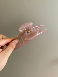 Detailed view of pink translucent resin hair claw clip with rhinestones and gold spring