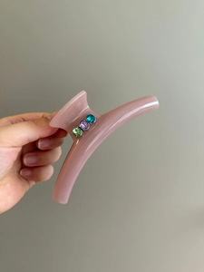 Detailed view of pink translucent hair claw clip with colorful inlaid rhinestones