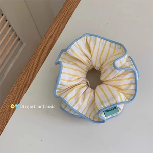 Detail of yellow striped oversized scrunchie with blue wavy trim and Hand Made label