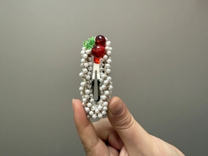 Détail d'une barrette cerise en perles faite main avec perles rouges et pince métallique