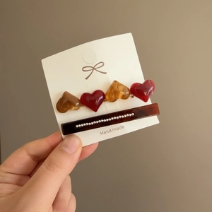 Detail of French hair clips with amber hearts and white pearls on a display card