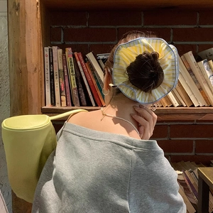 Oversized yellow striped scrunchie on a hair bun with a matching yellow bag and casual outfit