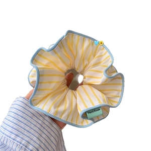 Oversized yellow striped scrunchie with blue wavy edges and a handmade green label