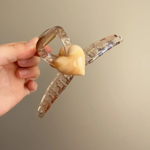 Detail view of a large amber jelly heart hair claw clip for thick hair styling