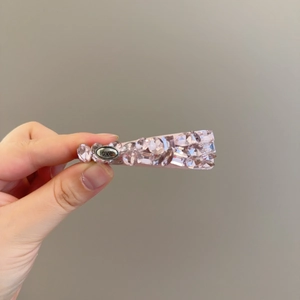 Détail d'une barrette en cristal rose avec nœud strass et plaque gravée love