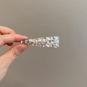 Détail de la pince à cheveux en strass avec plaque métallique gravée et finition polie