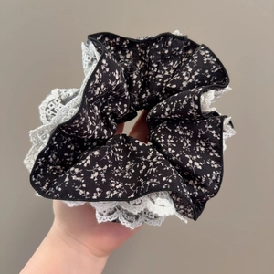 Détail d'un chouchou floral en tissu avec bordure en dentelle blanche et volants