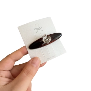 Brown tortoiseshell acetate hair clip with silver flower and pearl on white card