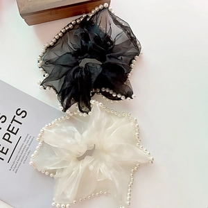 Détail de chouchous en tulle surdimensionnés noir et crème ornés de perles nacrées fines