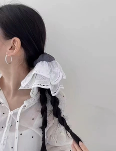 Detailed view of layered lace scrunchie with floral embroidery on a braided hairstyle