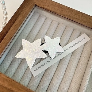 Détail macro d'une barrette étoile blanche scintillante pour enfants sur coffret velours