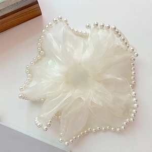 Détail d'un chouchou en organza blanc orné de perles synthétiques élégantes sur les bords