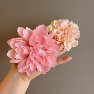 Hand holding two layered multi-colored floral hair clips in deep pink and light peach tones