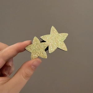 Gros plan de barrettes étoiles jaunes pailletées avec design double étoile pour enfants