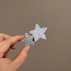Gros plan sur des barrettes double étoile avec paillettes irisées bleues sur base métal