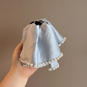 Detail of light blue satin hair claw clip featuring elegant white pearl bead edges