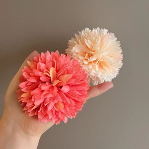 Detailed macro view of large pink and cream fabric flower petal hair clips held in hand