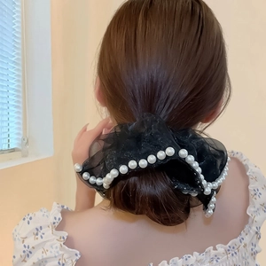 Chouchou géant en tulle noir avec perles blanches élégantes sur une coiffure en chignon