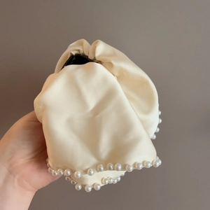 Detail of creamy white satin hair scrunchie with delicate pearl edge trim for women