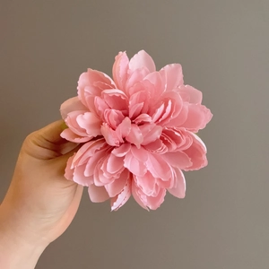 Detail showing layers of pink fabric flower petals on a 3D floral hair clip accessory