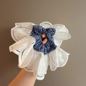 Detail of blue plaid fabric and white hollow lace ruffles on a large scrunchie