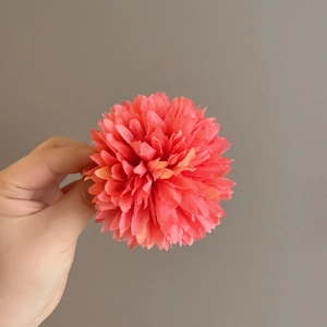 Macro view of multi-layered coral pink fabric flower hair clip with petal details