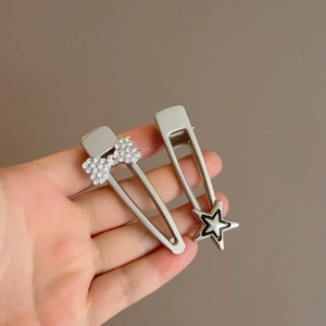 Détail de barrettes argentées Y2K avec étoile et nœud en strass tenues à la main