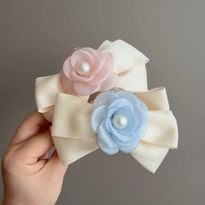 Gros plan de pinces à cheveux à fleurs en résille avec perles et nœuds en satin
