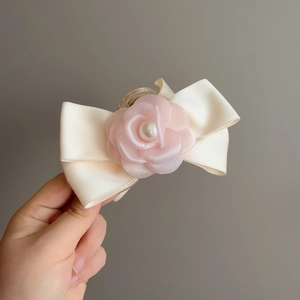 Détail d'une pince à cheveux en ruban de satin avec fleur en mousseline et perle