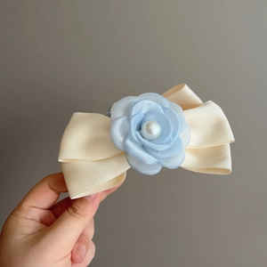 Vue détaillée d'une barrette en satin beige avec rose bleue et perle artificielle