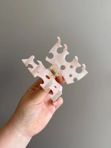Dettaglio di molletta per capelli in acetato rosa marmorizzato con design a intaglio