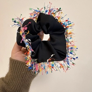 Detail of black satin scrunchie featuring vibrant multi-color fringe and tassel trim
