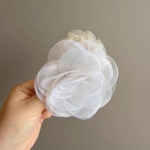 Gros plan sur les pétales en organza blanc d'une grande pince à cheveux fleur de camélia