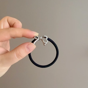 Hand holding a chic elastic hair tie with silver metallic bow for women's ponytail