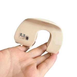 Pince à cheveux en acétate beige en forme de U avec emblème H en métal et strass brillant