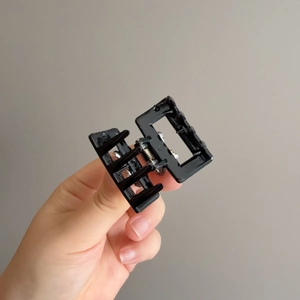 Minimalist black glossy rectangular claw clip with hollow bow design and metal spring