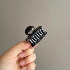 Elegant black glossy bow hair claw clip with rhinestones for a ponytail hairstyle