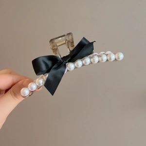 Détail d'une pince à cheveux en résine ambre avec perles et nœud en ruban de soie noir