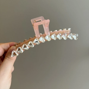 Dettaglio della clip per capelli rosa traslucida con strass scintillanti a cuore