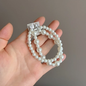 Élastique à cheveux double rangée en perles avec fermoir carré en argent tenu à la main