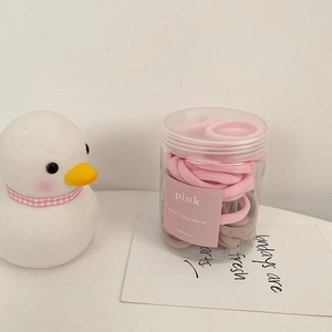 Gros plan d'élastiques à cheveux roses et marrons dans un pot avec une figurine de canard