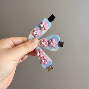 Detail view of blue checkered hair clips with pink flowers and heart-shaped rhinestones