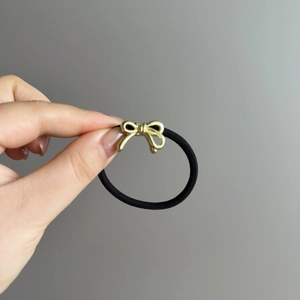 Élastique à cheveux noir avec un pendentif nœud papillon en métal doré poli