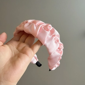 Détail d'un serre-tête en satin plissé rose avec finition brillante et embouts antidérapants